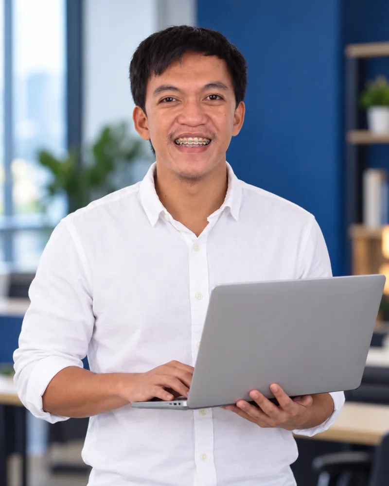 Charlie Hera smiling and holding a laptop